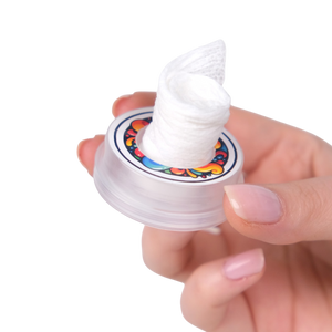 Hand holding a small container with white cream on a white background