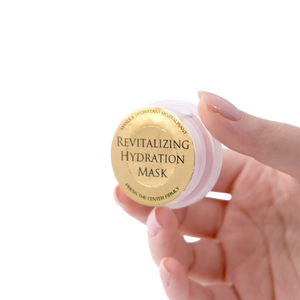 Hand holding a revitalizing hydration mask container with a gold label on a white background