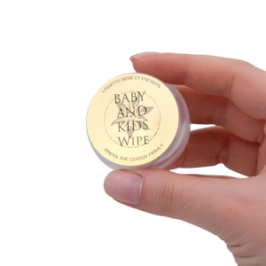 Hand holding a small container labeled 'Baby and Kids Wipe' against a white background