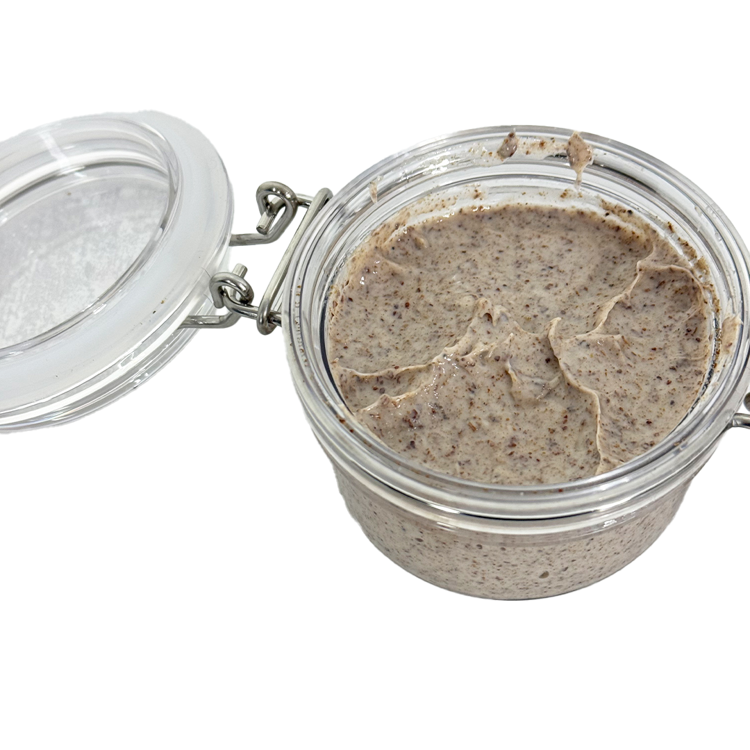 Glass jar with a metal lid containing a brown paste on a white background