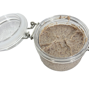 Glass jar with a metal lid containing a brown paste on a white background