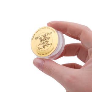 Hand holding a small container of unscented hand and face wipes with a gold lid.