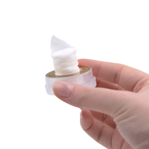 Hand holding a small container of white cream against a white background